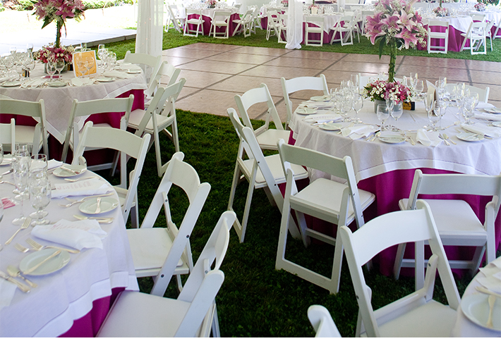 Round tables with white tablecloths and pink accents are set with glassware, plates, and floral centerpieces. White folding chairs surround the tables, and the event appears to be outdoors on grass under a tent—an elegant setup perfect for anyone seeking memorable things to do in Springfield, Ohio.